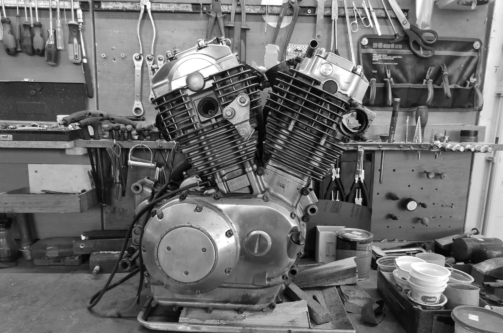 A motorcycle V-twin engine on a workbench, in black and white