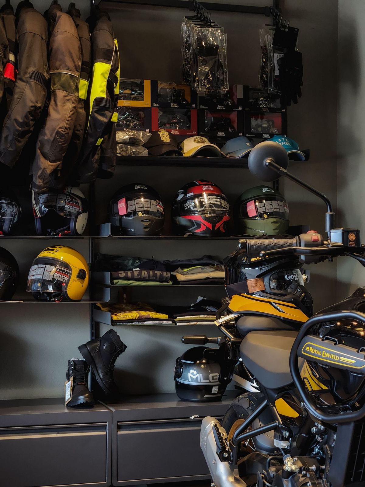 Shelves of motorcycle helmets above a rail of riding jackets